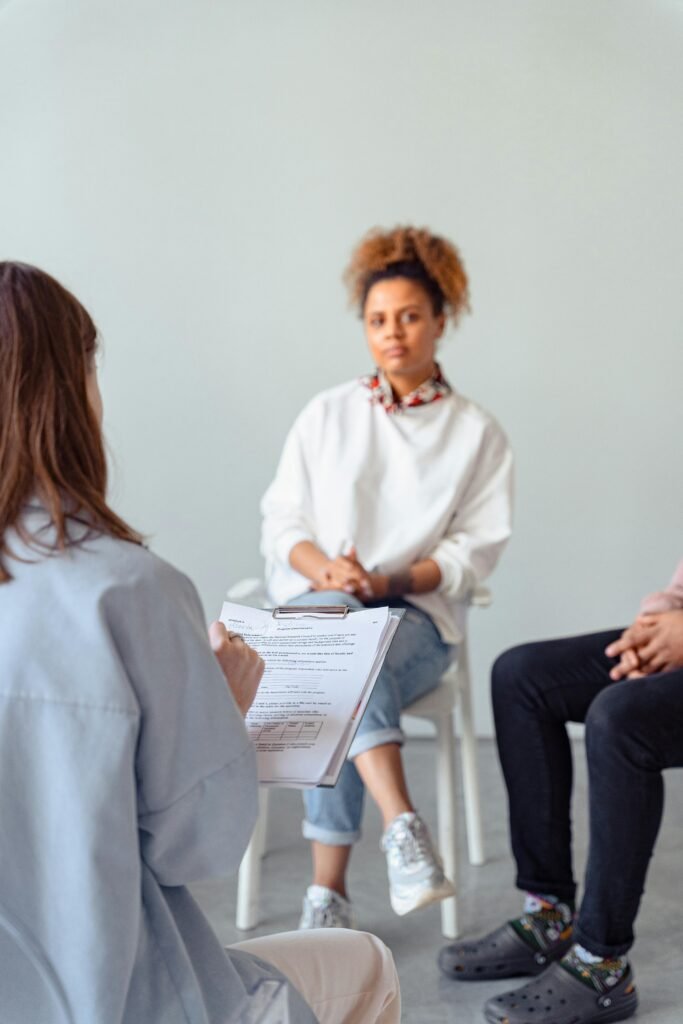 Counselor and diverse woman in a therapy session discussing mental health.