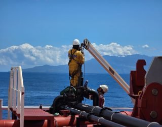 Workers on an offshore oil platform in Mozambique, performing maintenance work under clear skies.